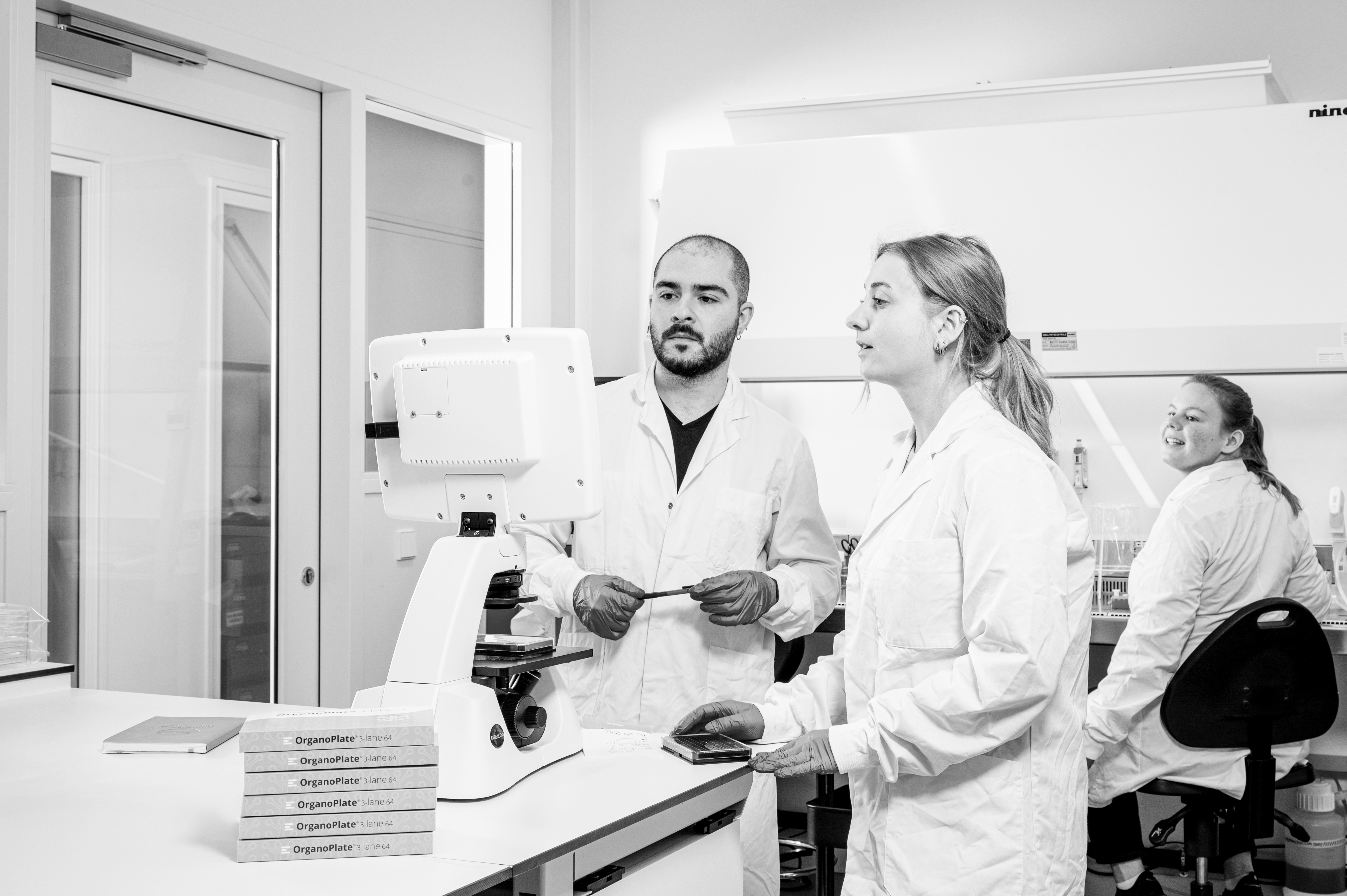 Scientists in white coats working together in a laboratory with microscope