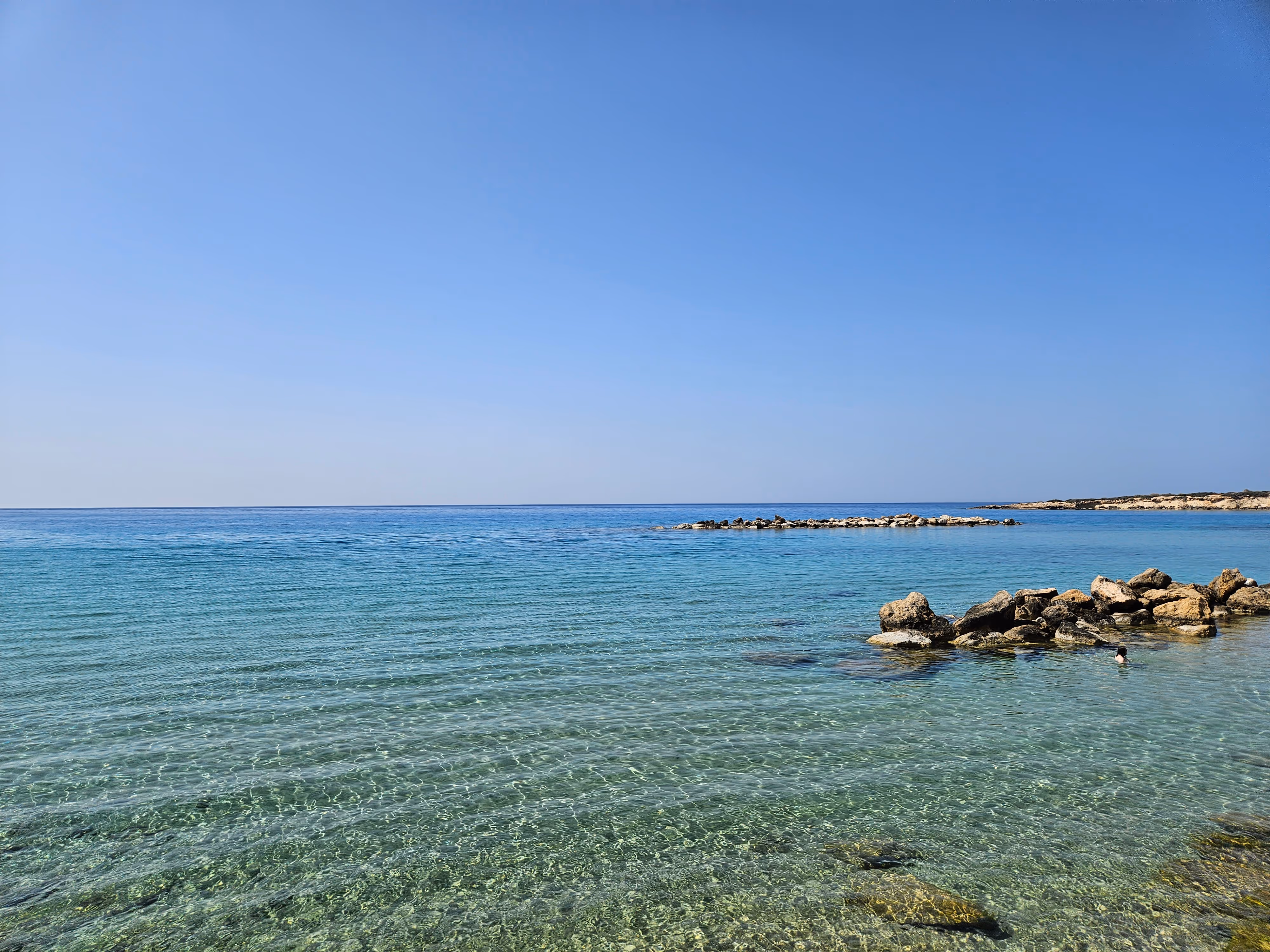A picture of a historical place, Aphrodite`s rock, the image shows a beach filled with rocks