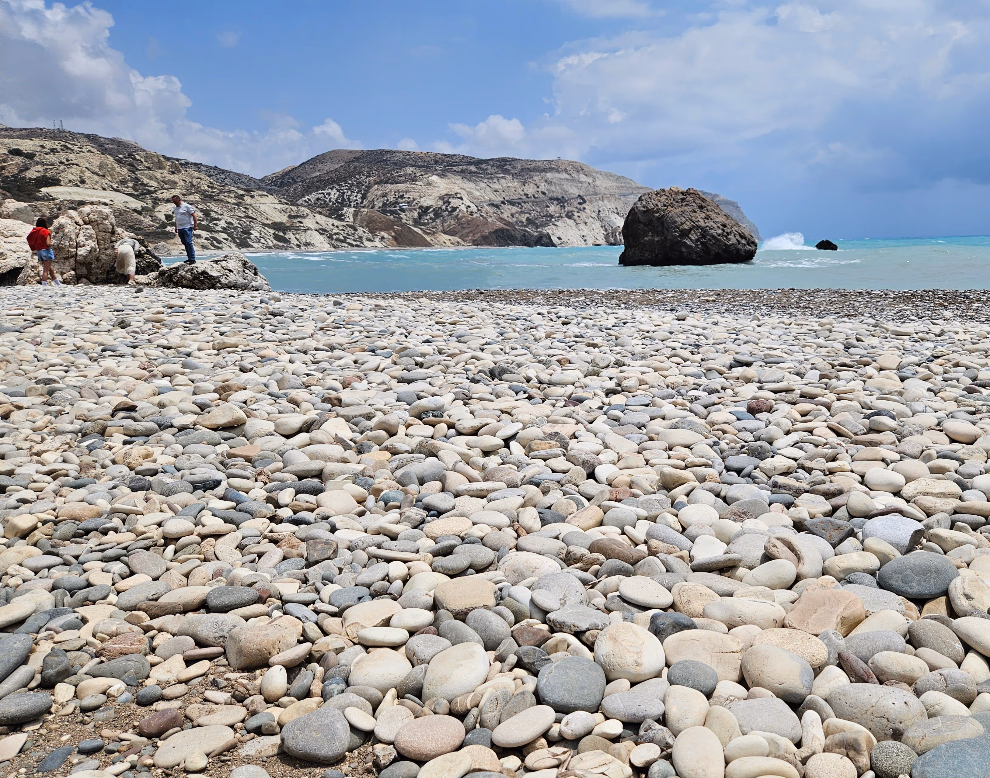 A picture of a historical place, Aphrodite`s rock, the image shows a beach filled with rocks