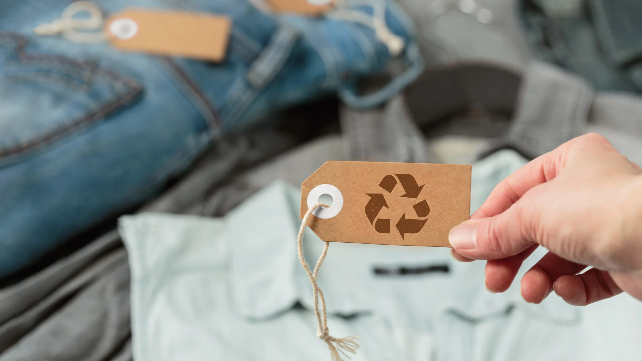 Recycling tag attached to a pair of jeans, promoting sustainable fashion and responsible garment disposal.