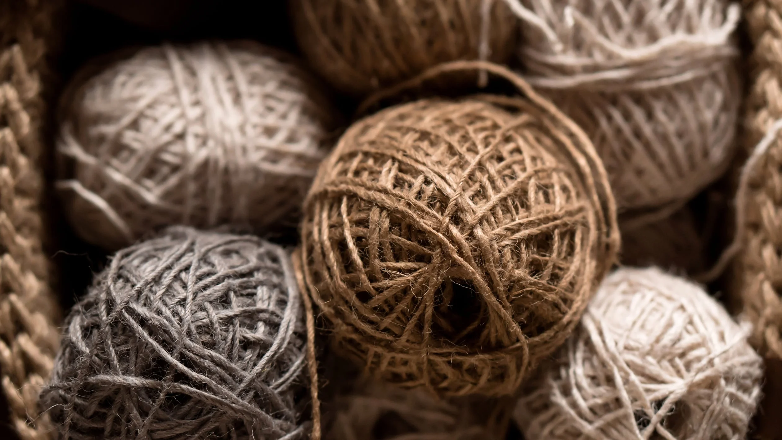 A colorful basket filled with various skeins of yarn in different textures and shades.