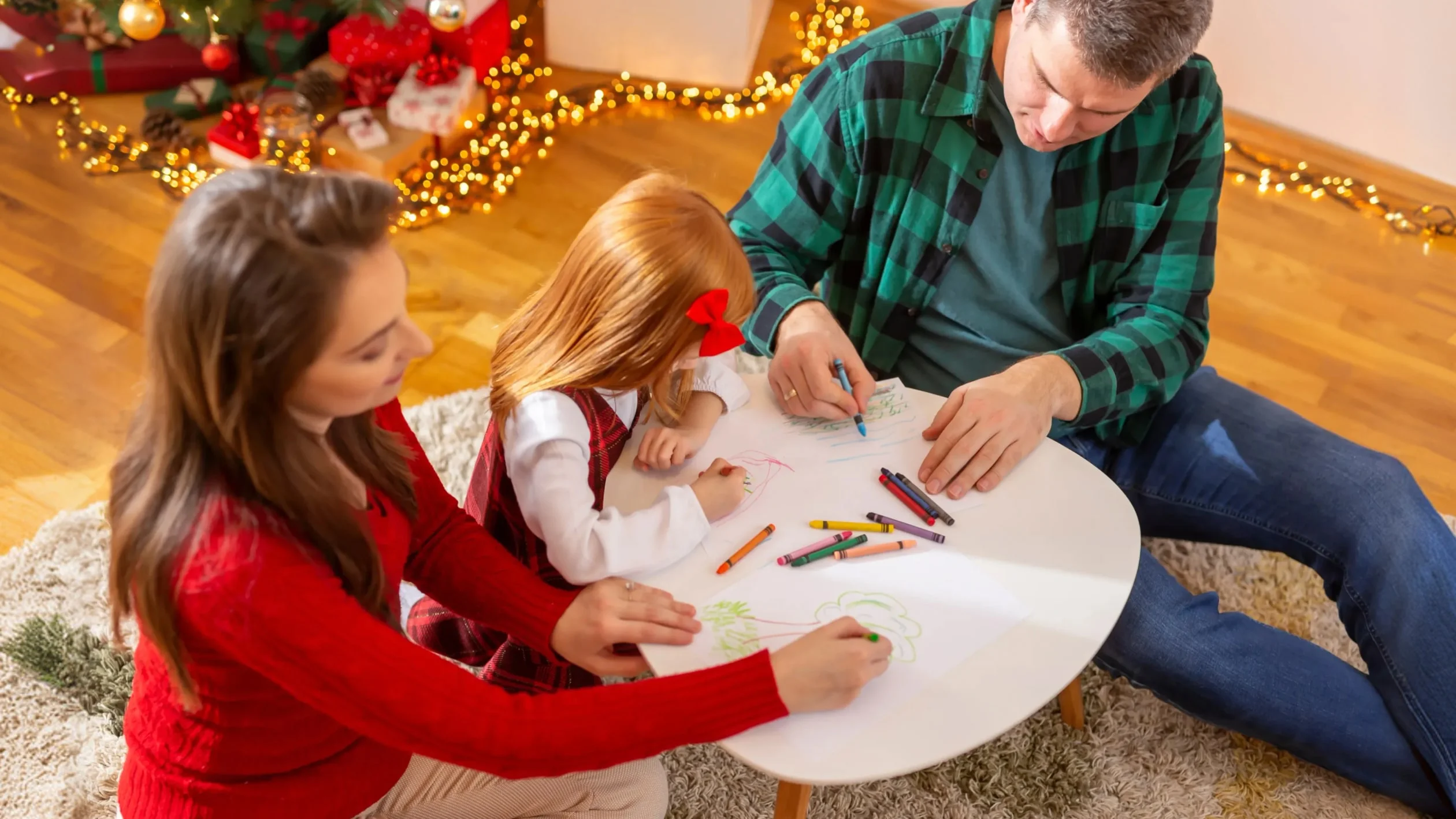 A family gathered around a table, actively drawing and brainstorming on a whiteboard together.