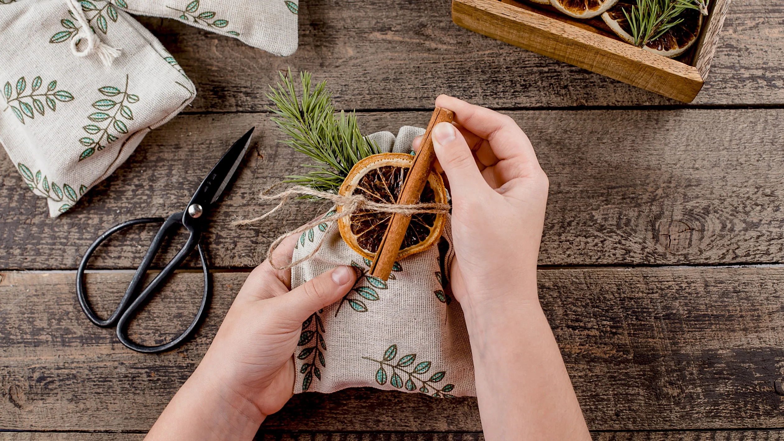 A person using scissors to cut a piece of fabric on a flat surface.