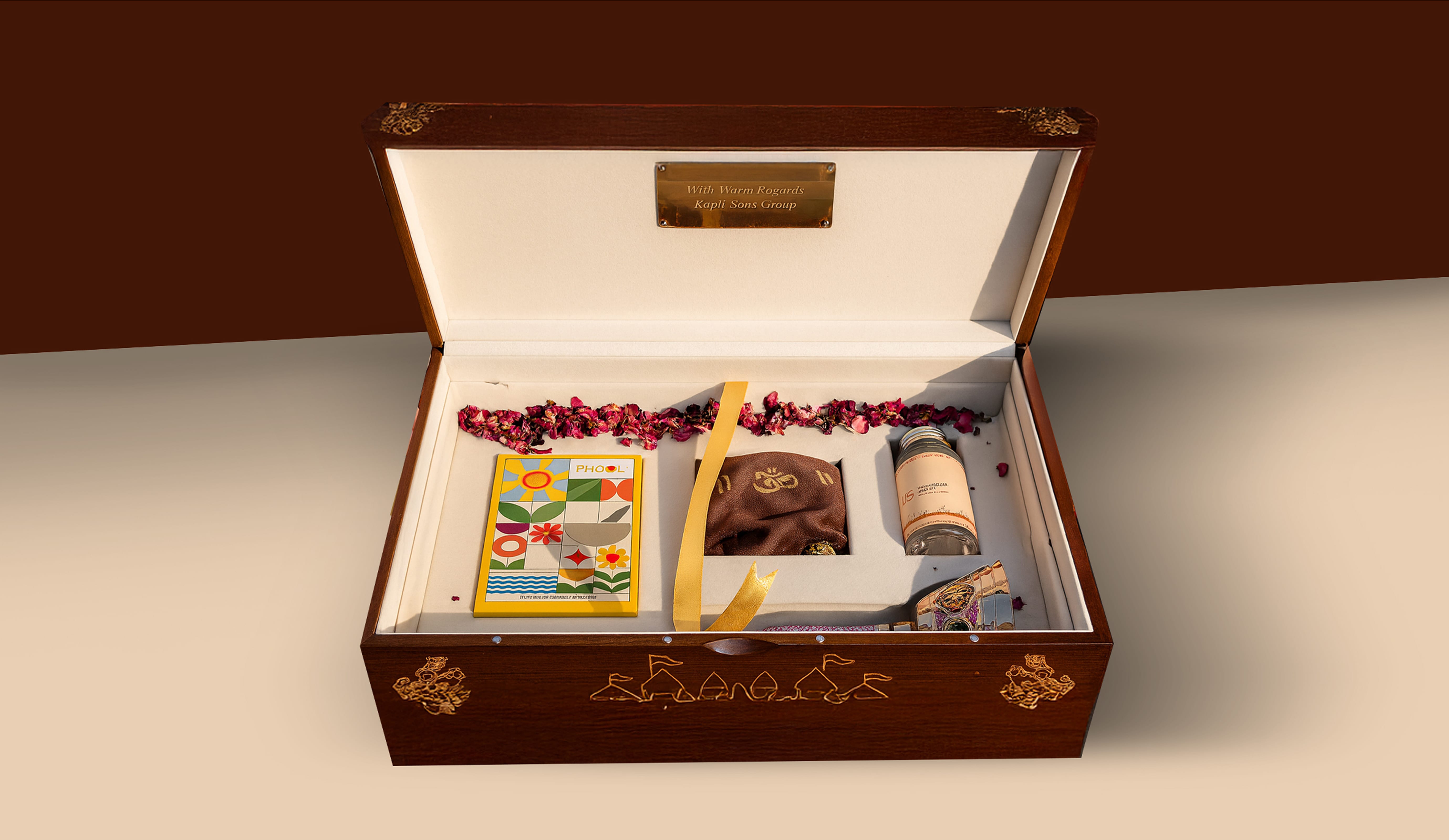 Open wooden gift box with floral decorations containing dried rose petals, a colorful card, a small brown pouch, a glass bottle, and a decorative item inside.