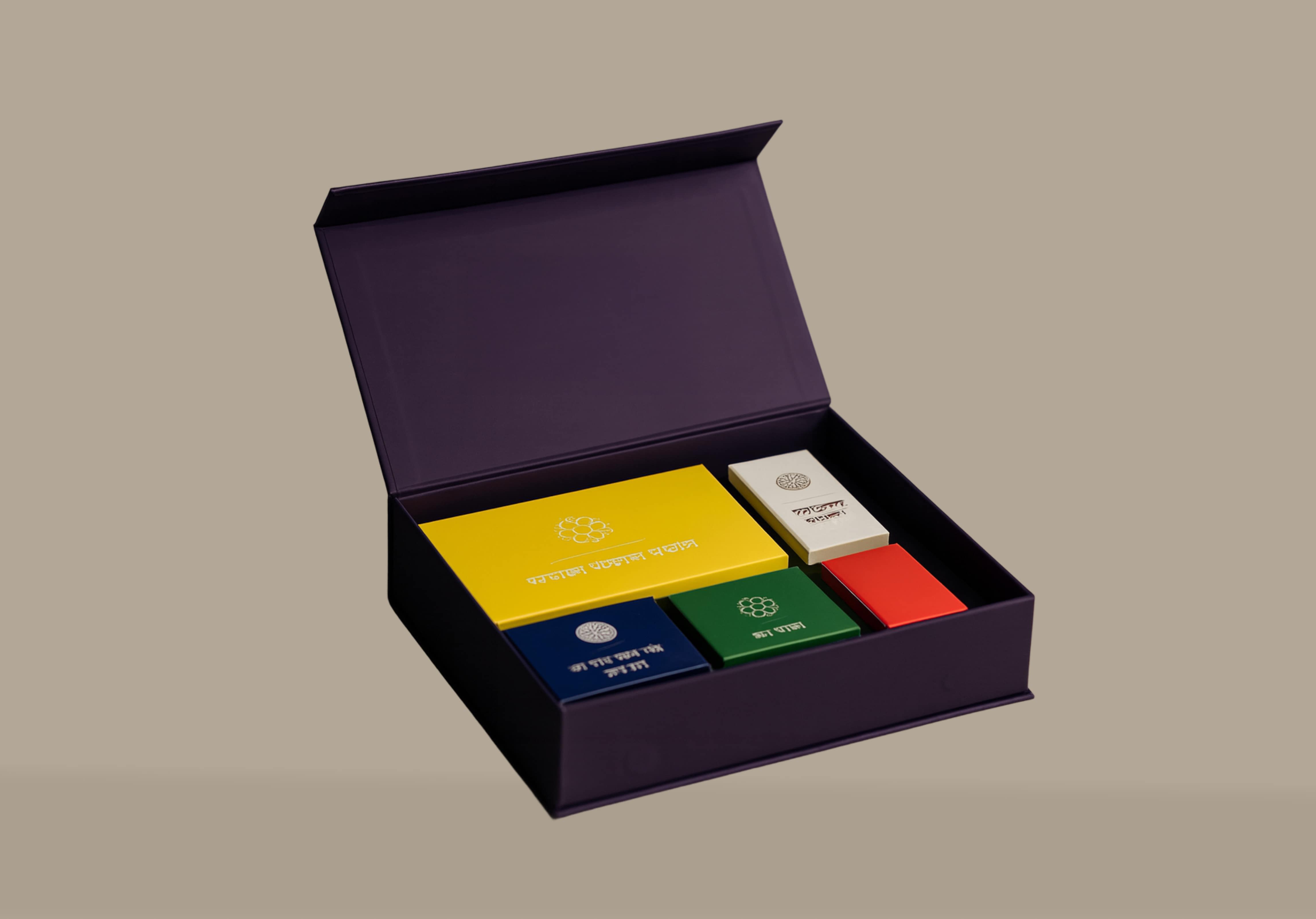 Open dark purple gift box containing five smaller colorful boxes in yellow, white, red, green, and blue with text and symbols on them.