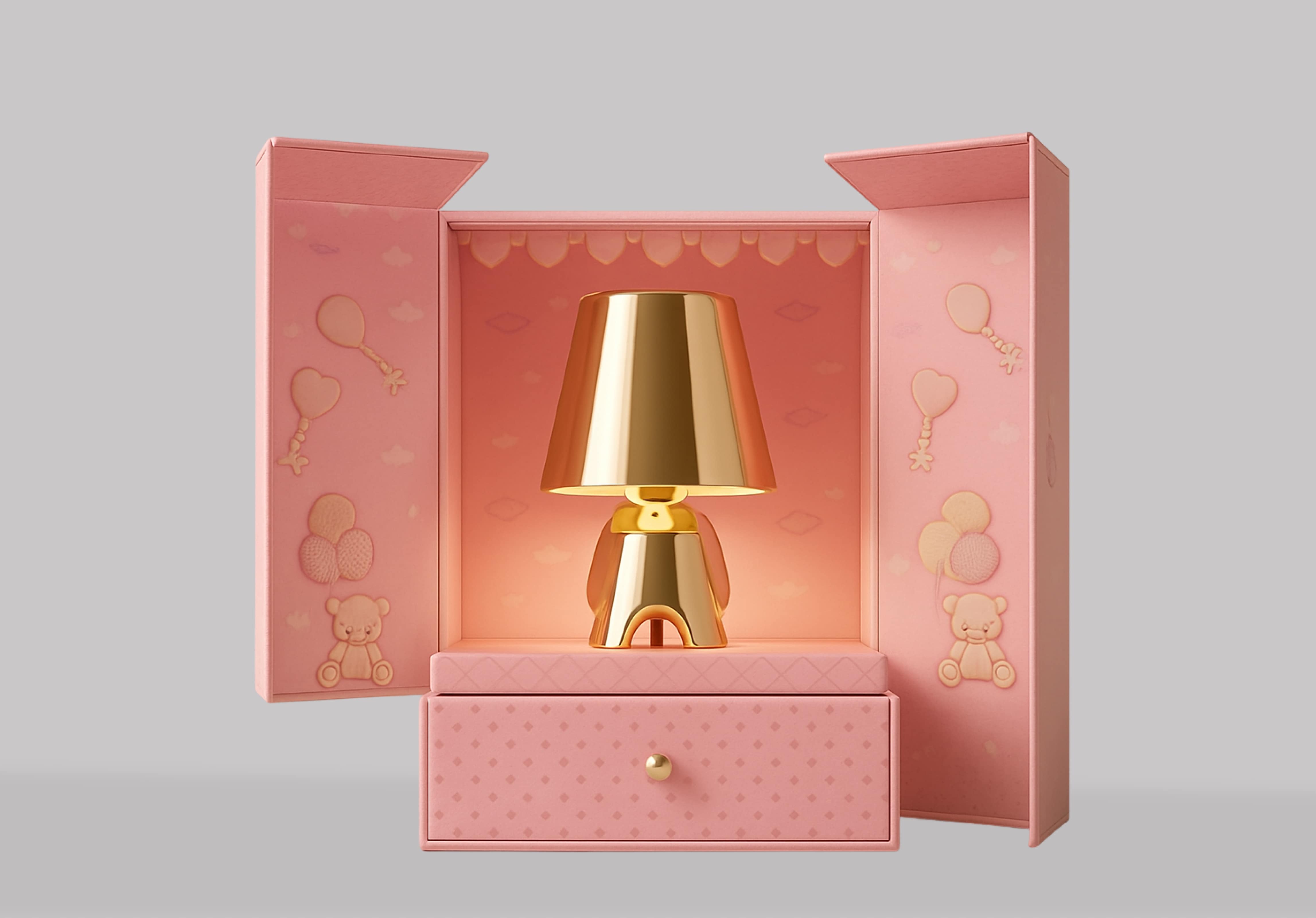 Golden metallic lamp shaped like a small figure inside an open pink decorative box with teddy bear and balloon designs.