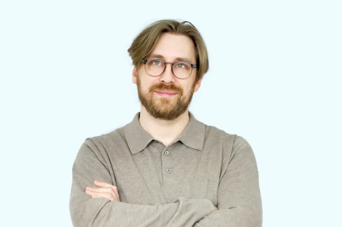 Arnold Kotra standing on a train platform near the tracks in a black and white photo.