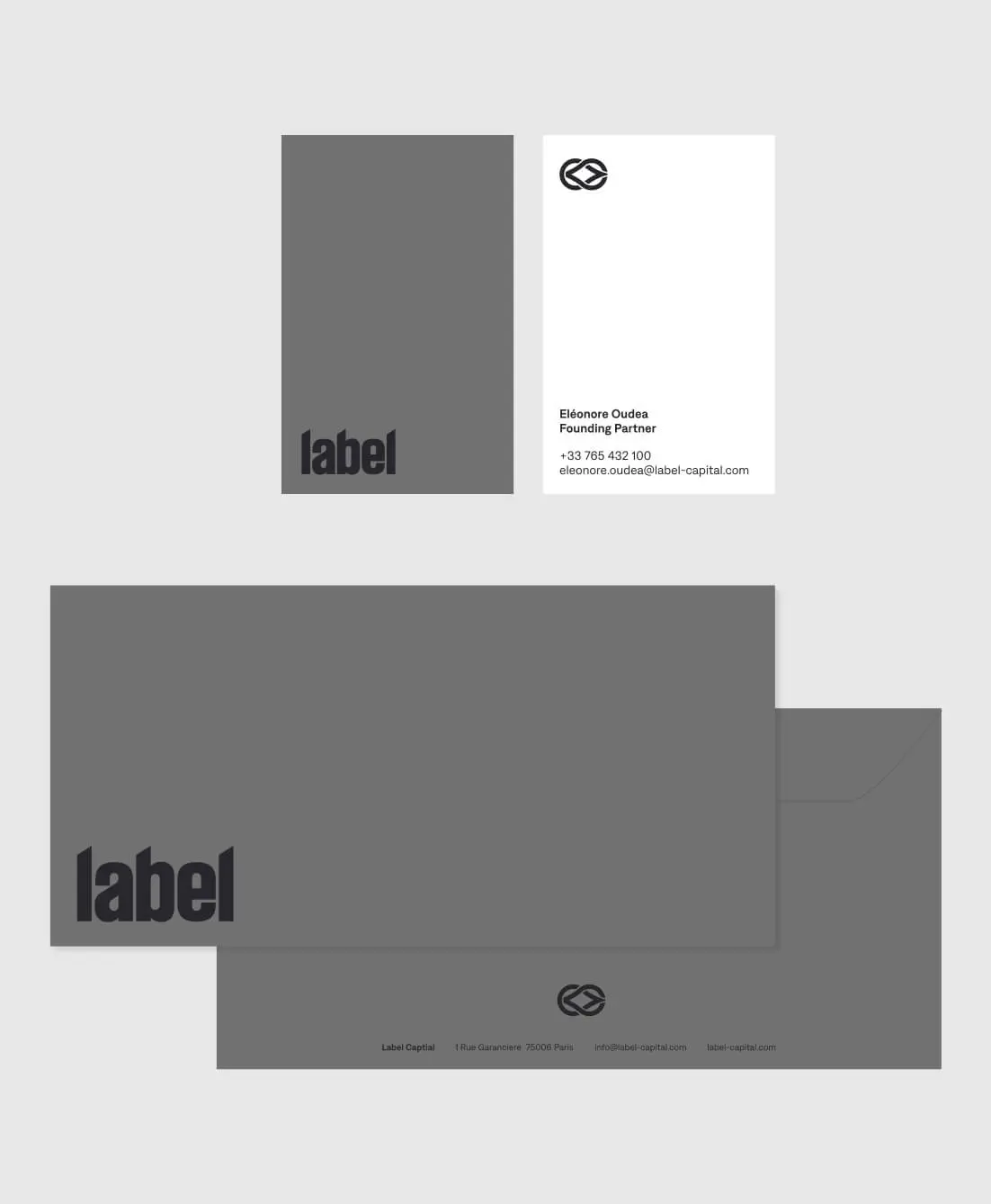 Set of monochrome stationery including a business card, folder, and envelope branded with 'label' and a circular double-chevron logo.