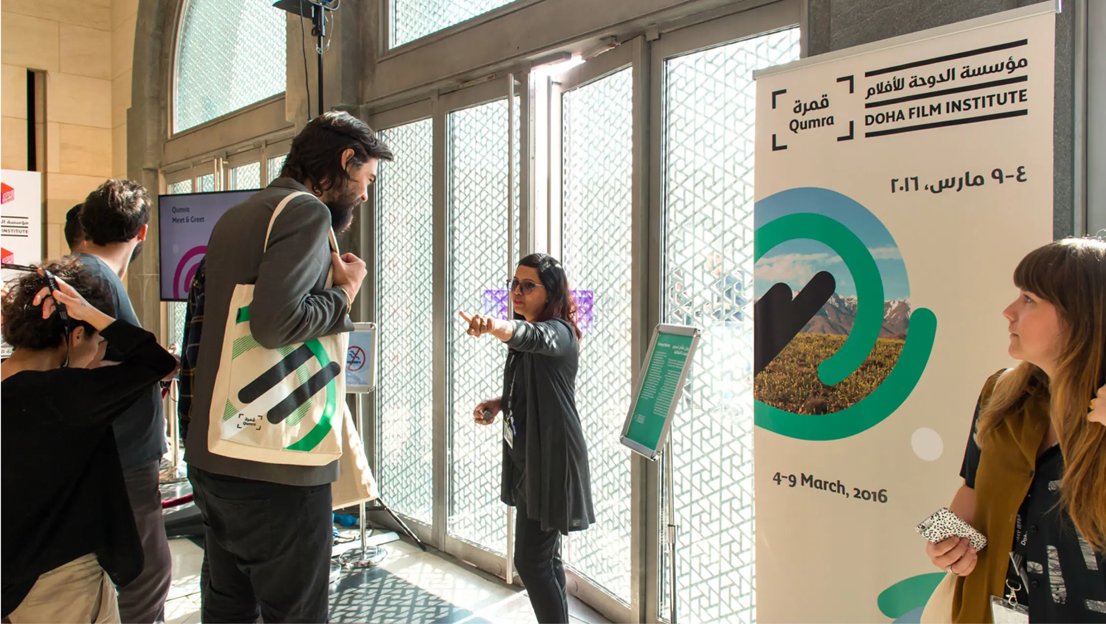 People interacting inside a venue near a Doha Film Institute Qumra 2016 event banner.