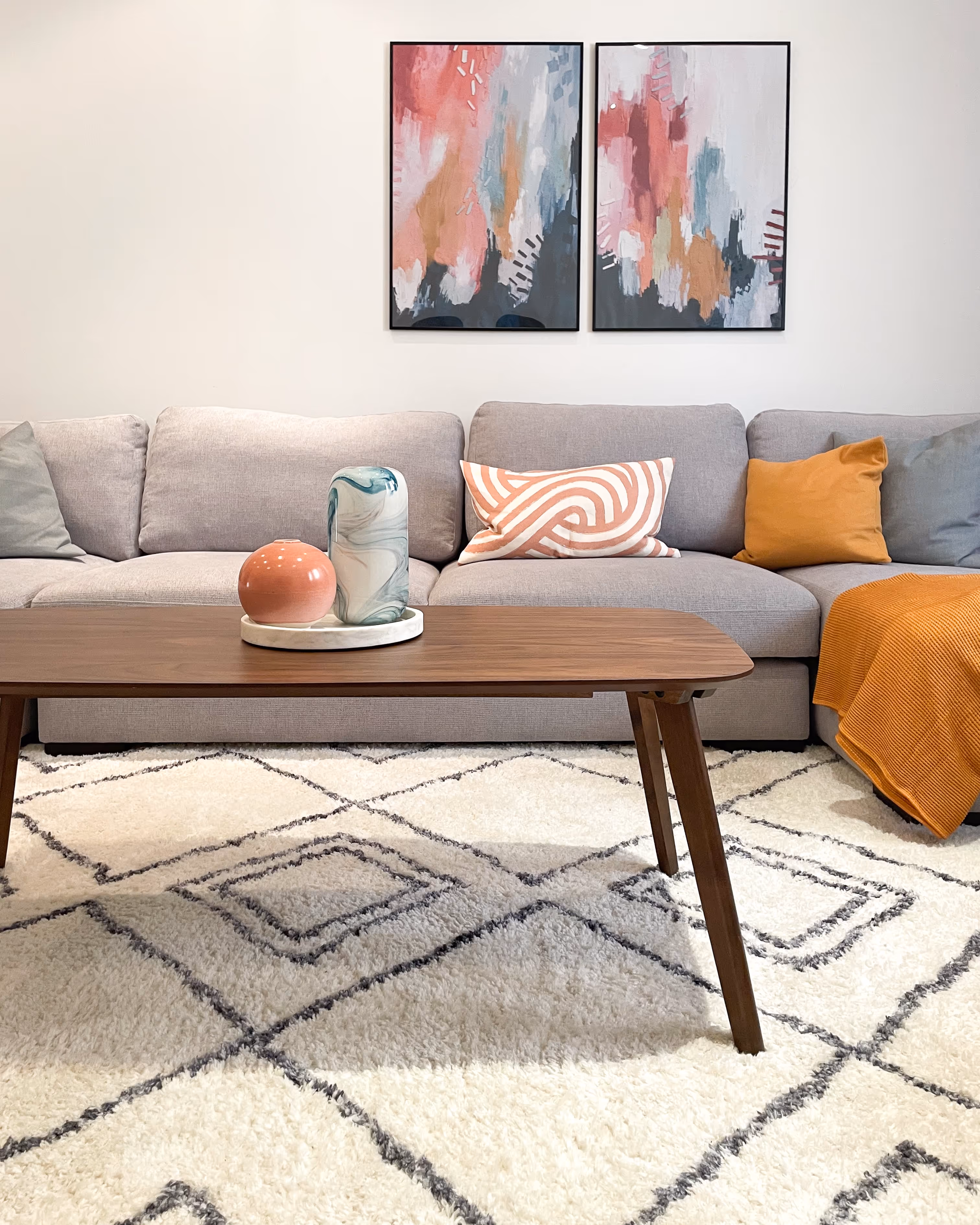 Modern living room with grey sectional sofa, abstract wall art, and decorative accents, showcasing custom interior design by Roberts Renovations.