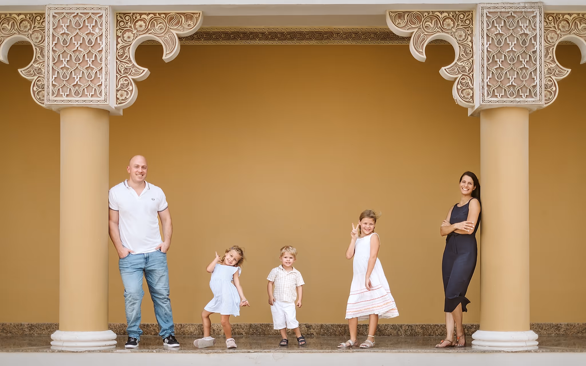 The Roberts family standing together in front of a golden ochre wall, reflecting the personal, family-run values behind Roberts Renovations.