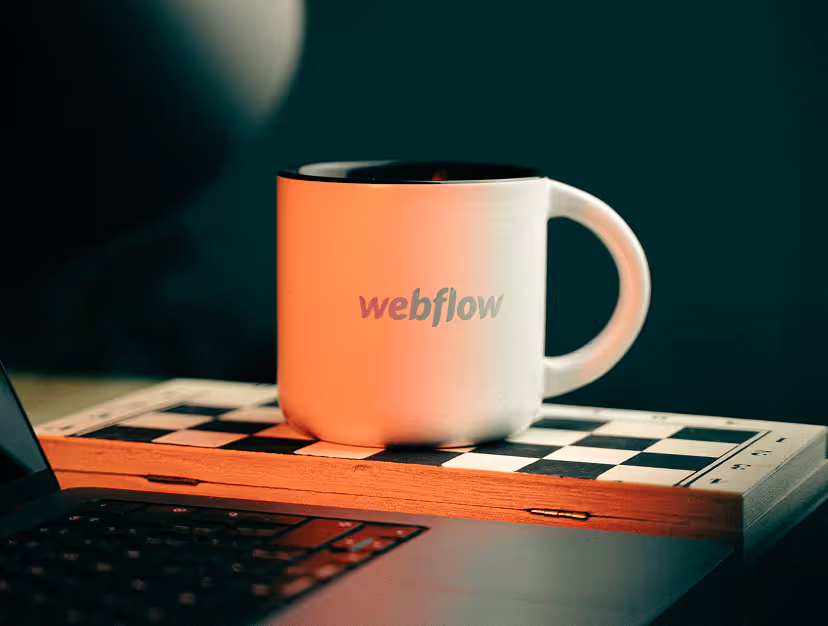 En kaffekopp på ett skrivbord med Webflow-logotyp