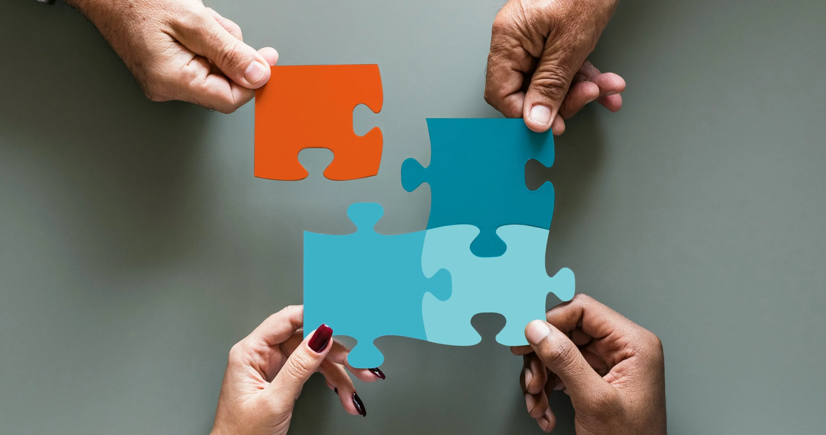 Verschiedene Hände bauen ein Puzzel.