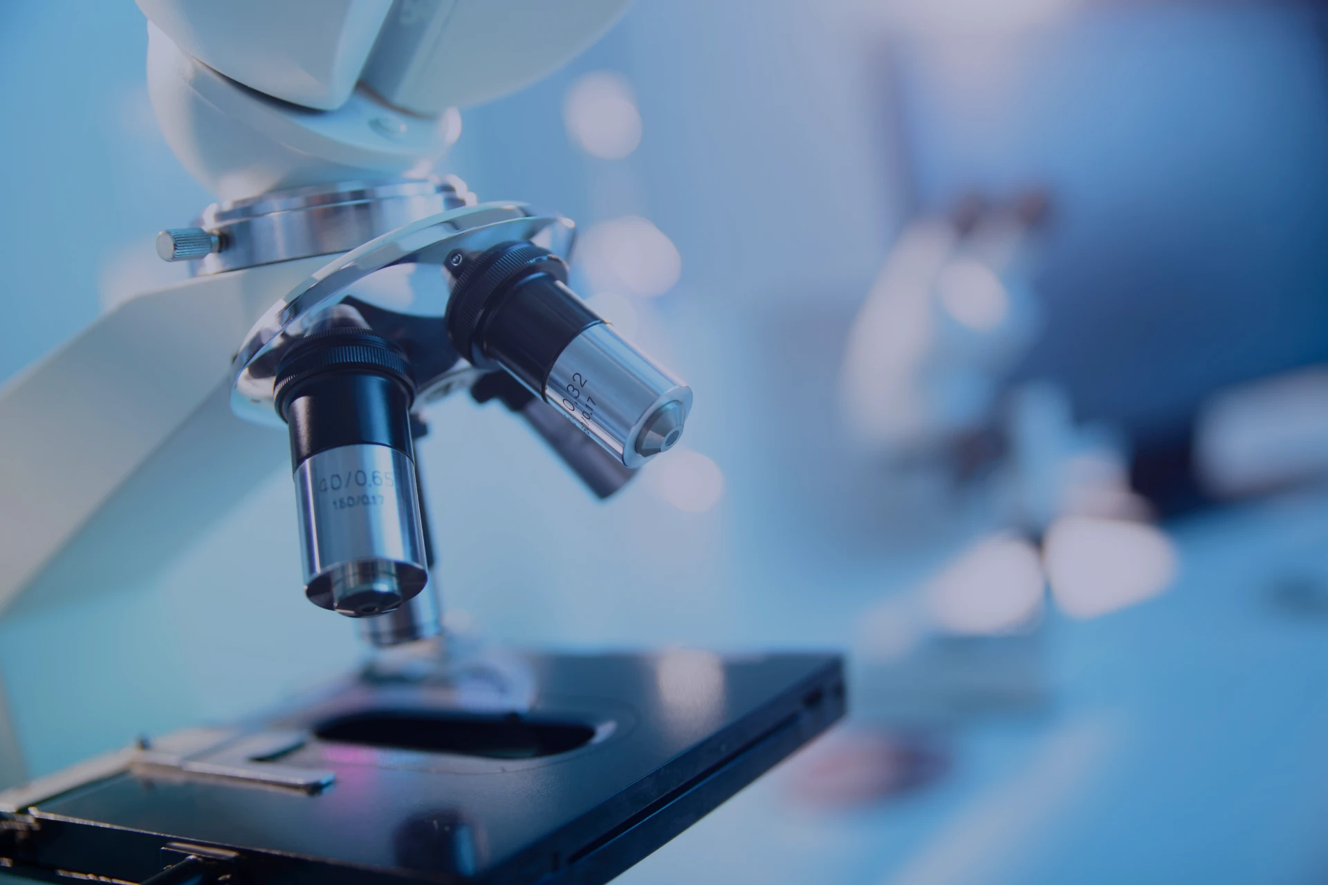 Microscópio em laboratório com foco em lentes e platô, ideal para estudos científicos e exames laboratoriais em ambientes médicos.