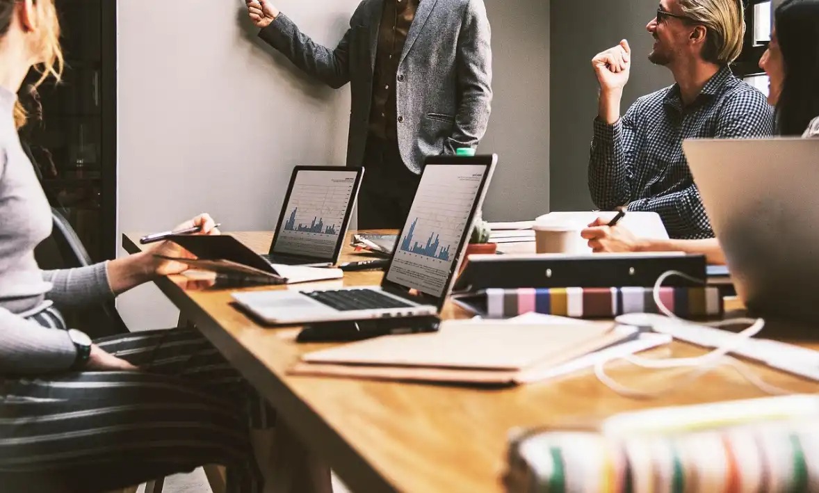 Reunião produtiva em ambiente de trabalho moderno, com profissionais discutindo ideias diante de telas de computador, ideal para otimização de desempenho em equipe.