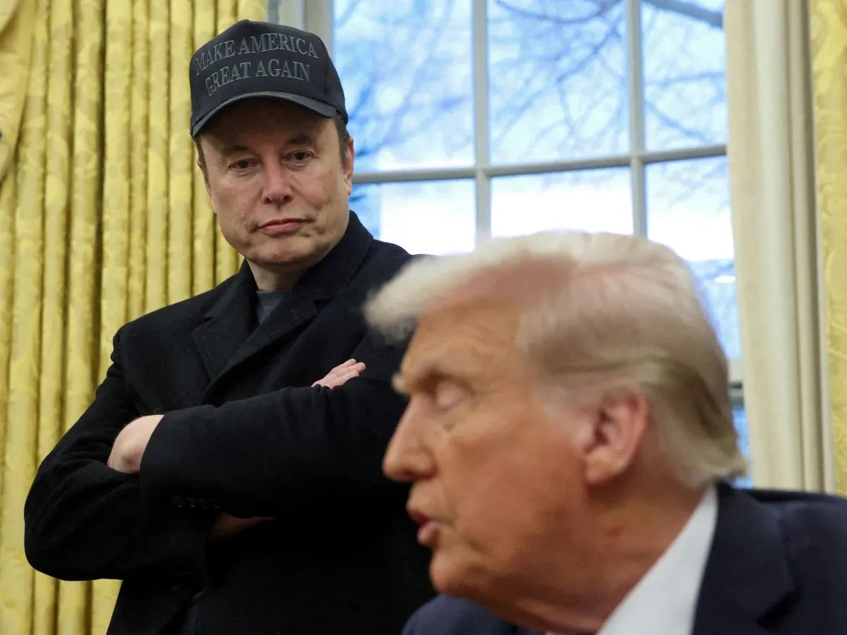 Elon Musk em um encontro no Salão Oval com Donald Trump, usando um boné que diz 'Make America Great Again'.
