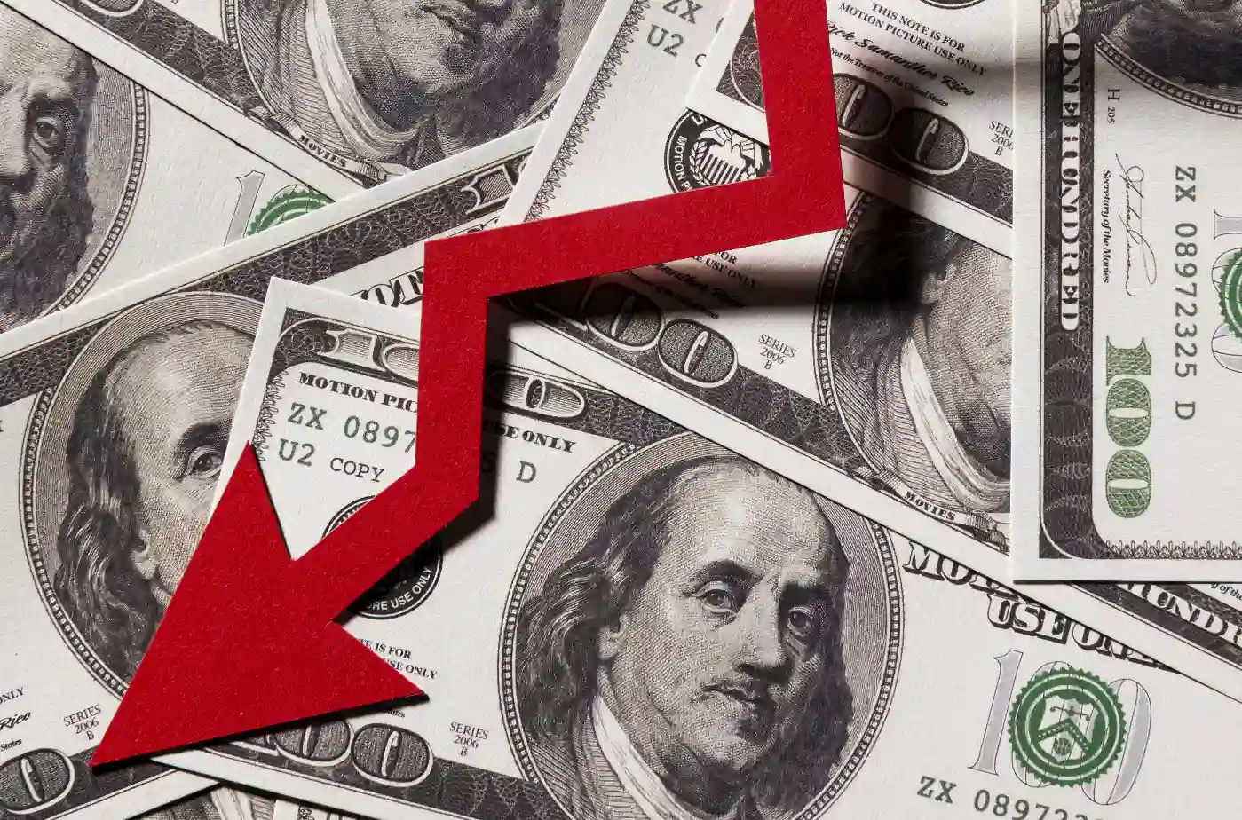 Imagem representando a alta inflação, com uma seta vermelha apontando para baixo sobre notas de dólar, simbolizando a desvalorização econômica.