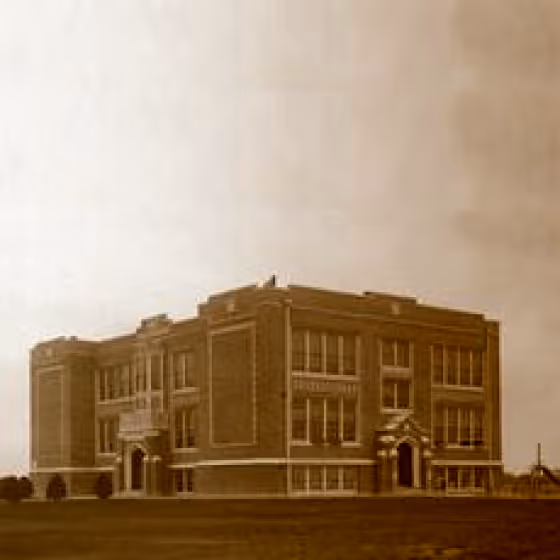 A pixelated photo of a two story building that is the first high-school in San Juan, Texas. The architecture is reminiscent of the Palazzo style of buildings found in larger schoolhouses of this time.