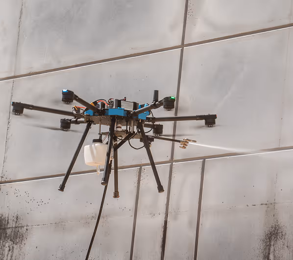 Drone cleaning a large glass building with a spray. The drone has multiple propellers and a mounted tank, highlighting technology in maintenance.
