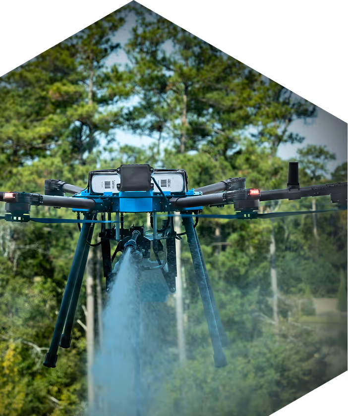 A large drone hovers over a lush, green landscape, emitting a misty spray. Tall trees form the backdrop, conveying a sense of innovation in nature.