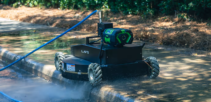 A robot equipped with a pressure washer cleans a wet street. It features a compact design with robust wheels and a green motor, conveying efficiency.