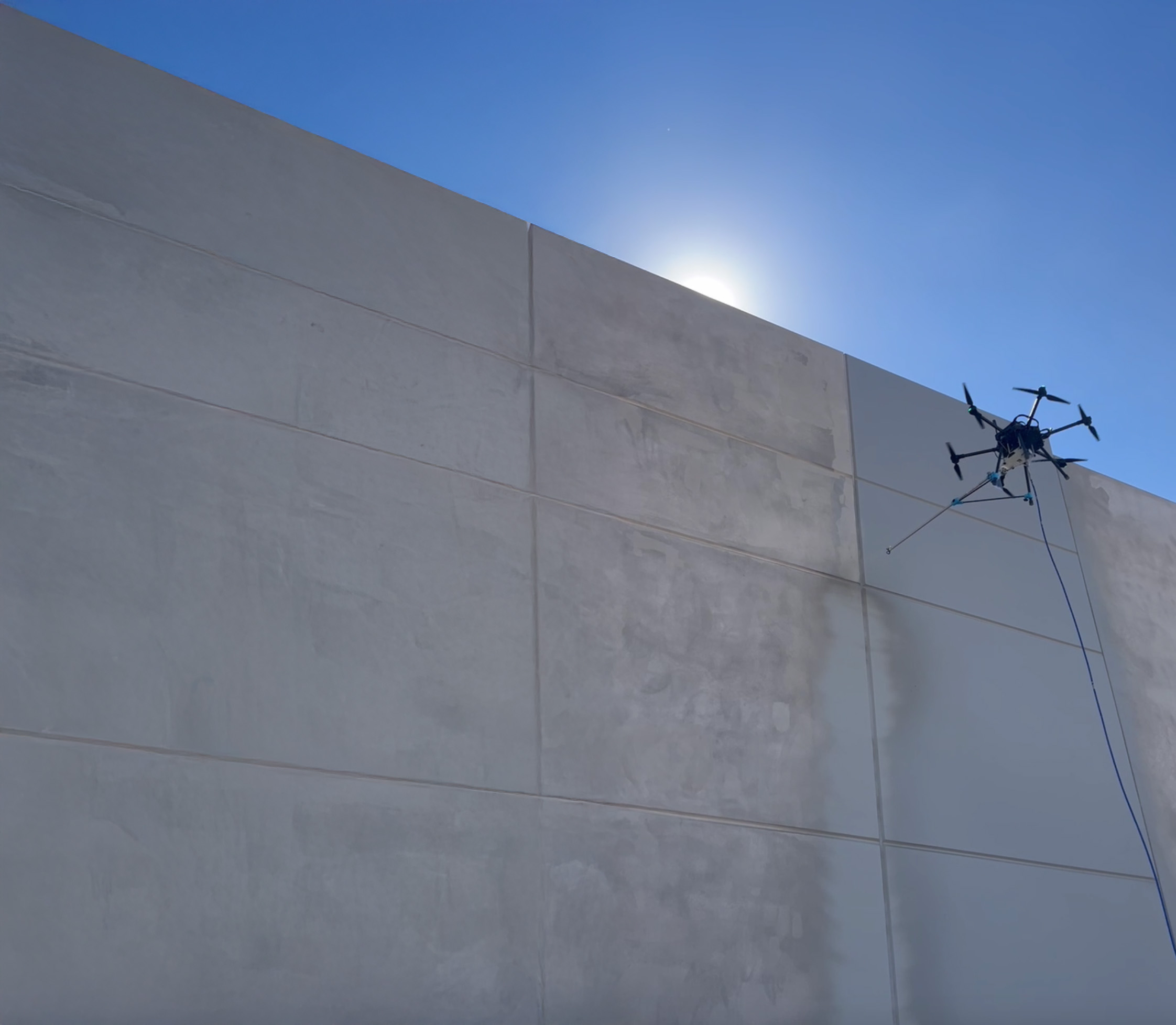 Sherpa Drone applying a stain to a large tilt-up concrete wall panel