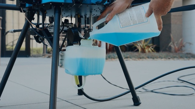 filling the drone chemical tank with a blue window cleaning solution