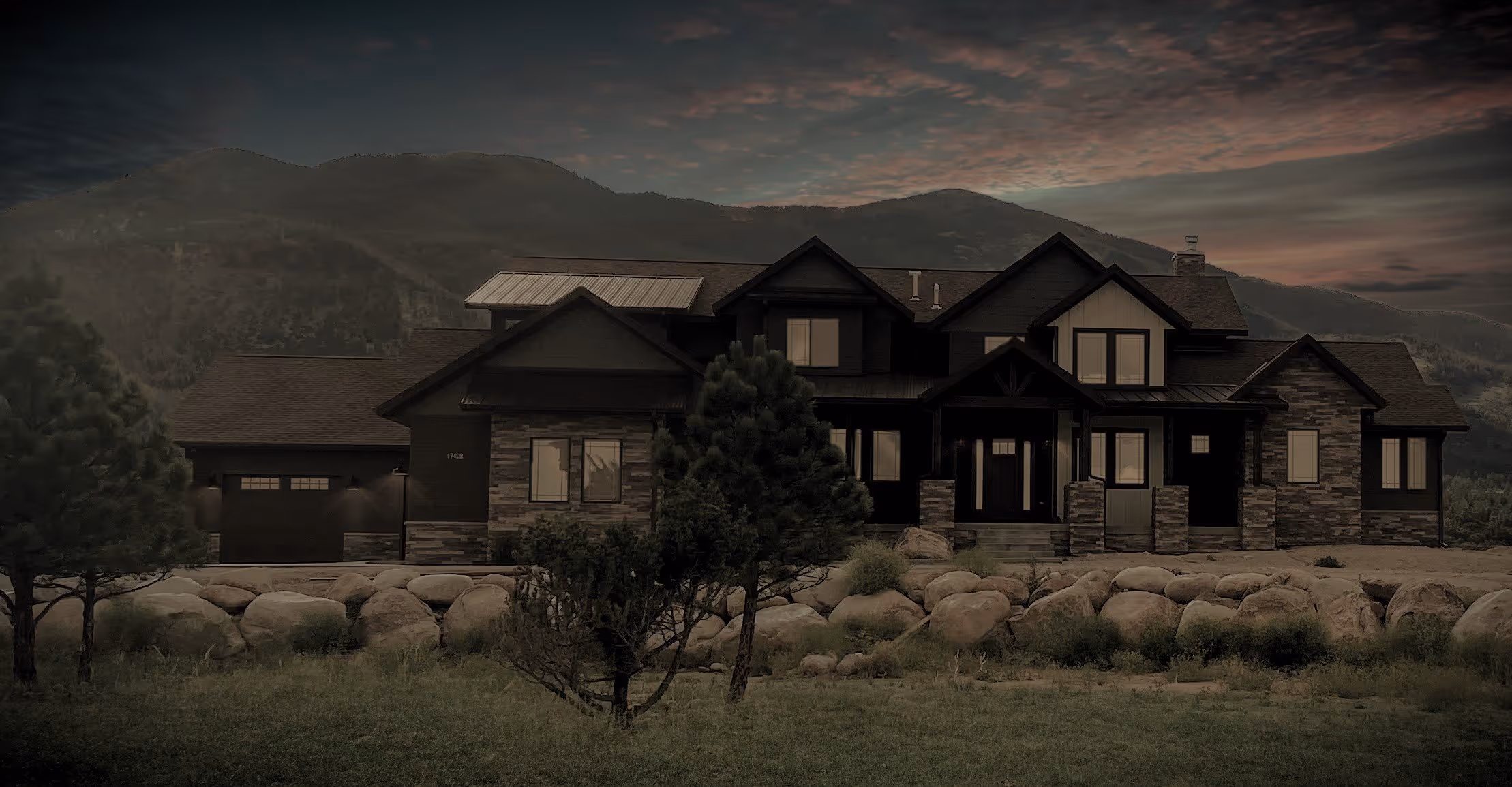 Moody dusk scene showing a large, craftsman style custom home with steep gables beneath a cloudy sky.