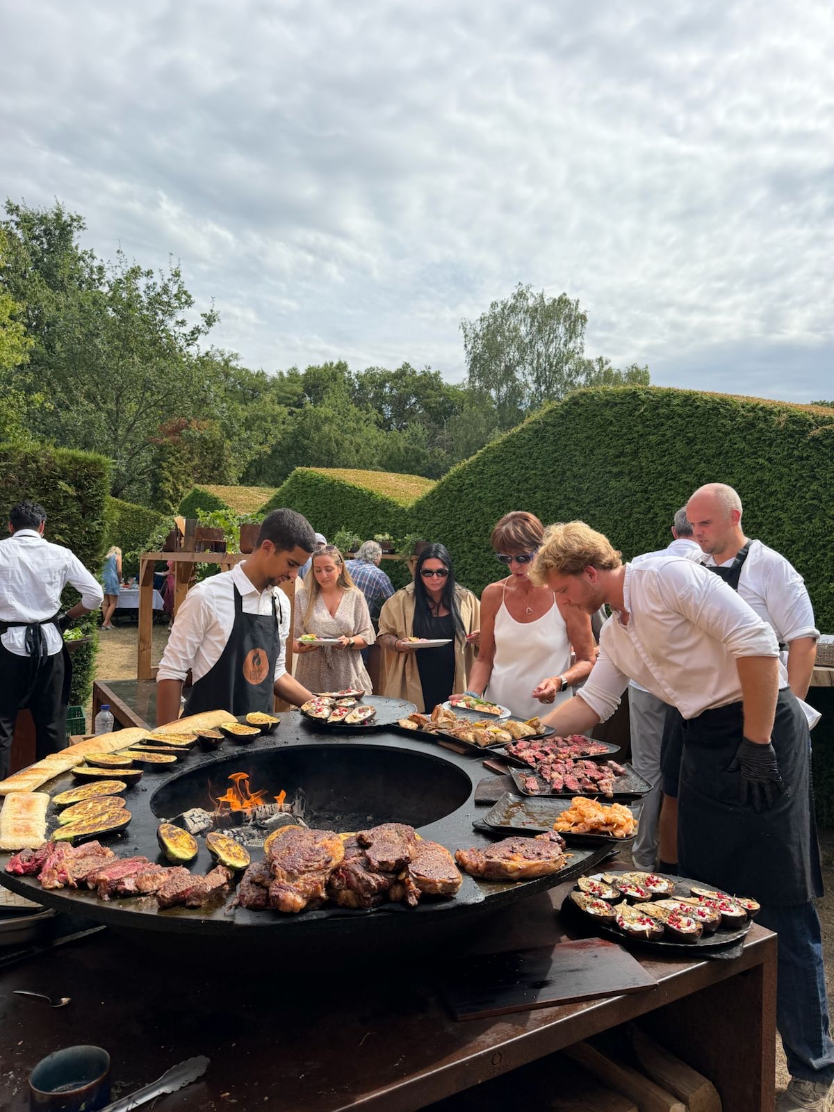 Gasten rond de vuurschaal-grill in de tuin van The Roots