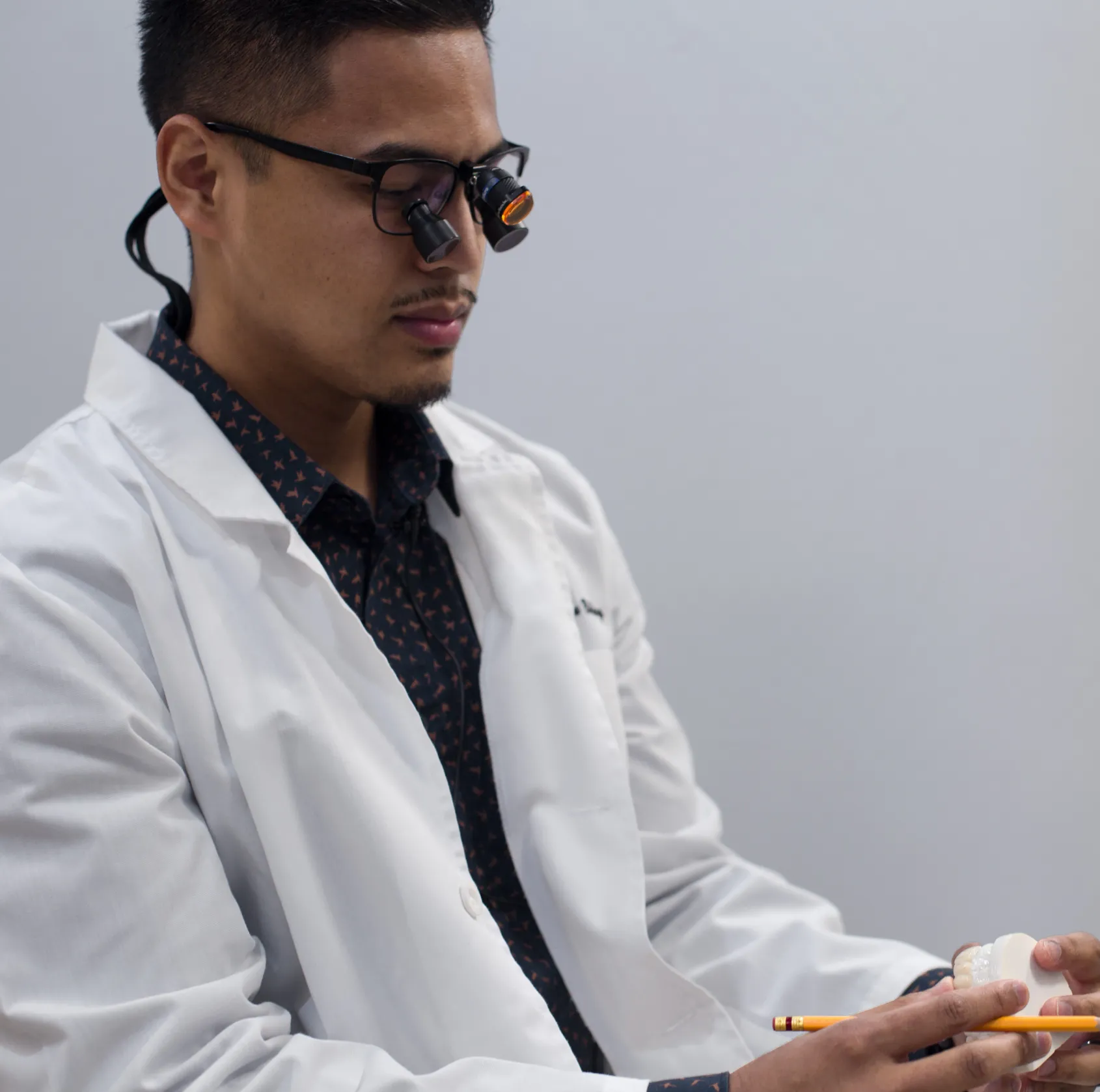 male in a lab coat and tie holding a cell phone  Dynamic Dental