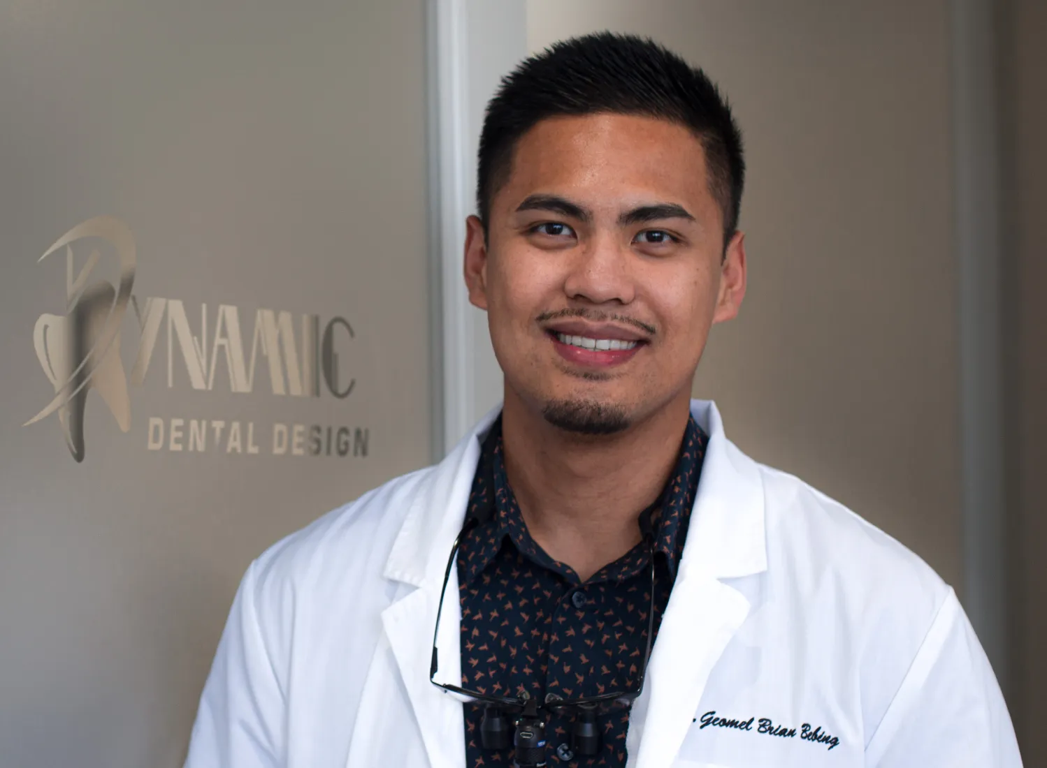 male in a white lab coat standing in front of a door Dynamic Dental