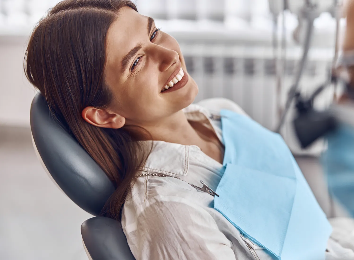 smiling woman in dental chair with blue bib and blue apron  Dynamic Dental