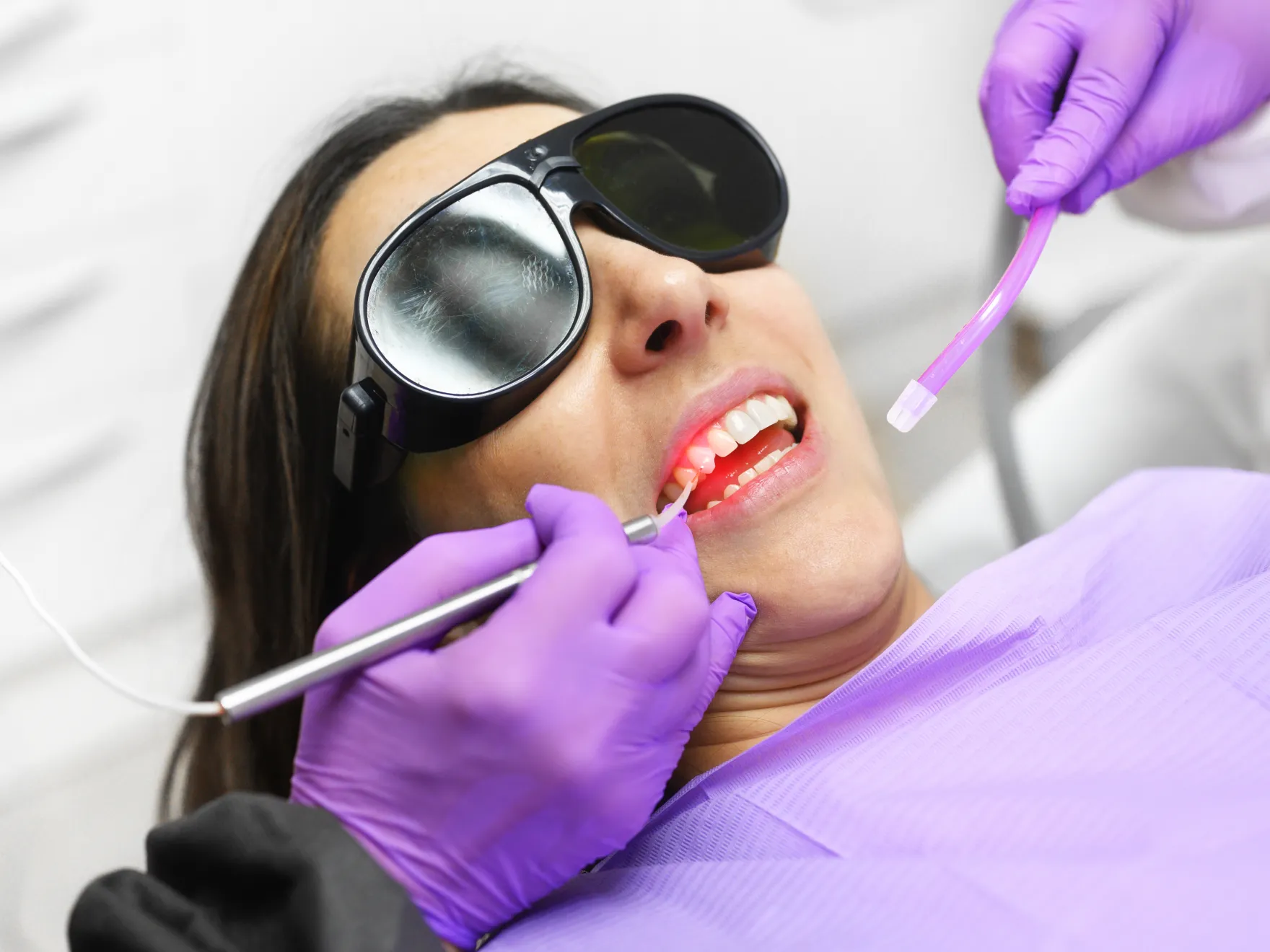 woman with sunglasses and purple gloves getting her teeth brushed  Dynamic Dental