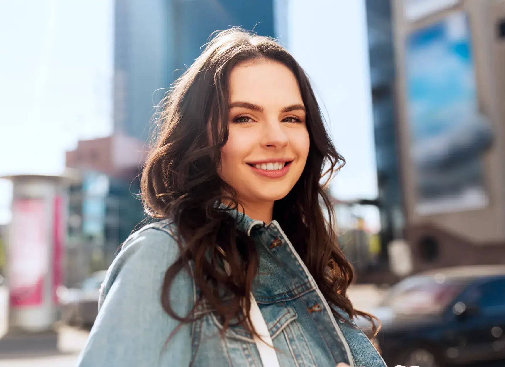 smiling woman in denim jacket holding a cell phone in her hand Dynamic Dental
