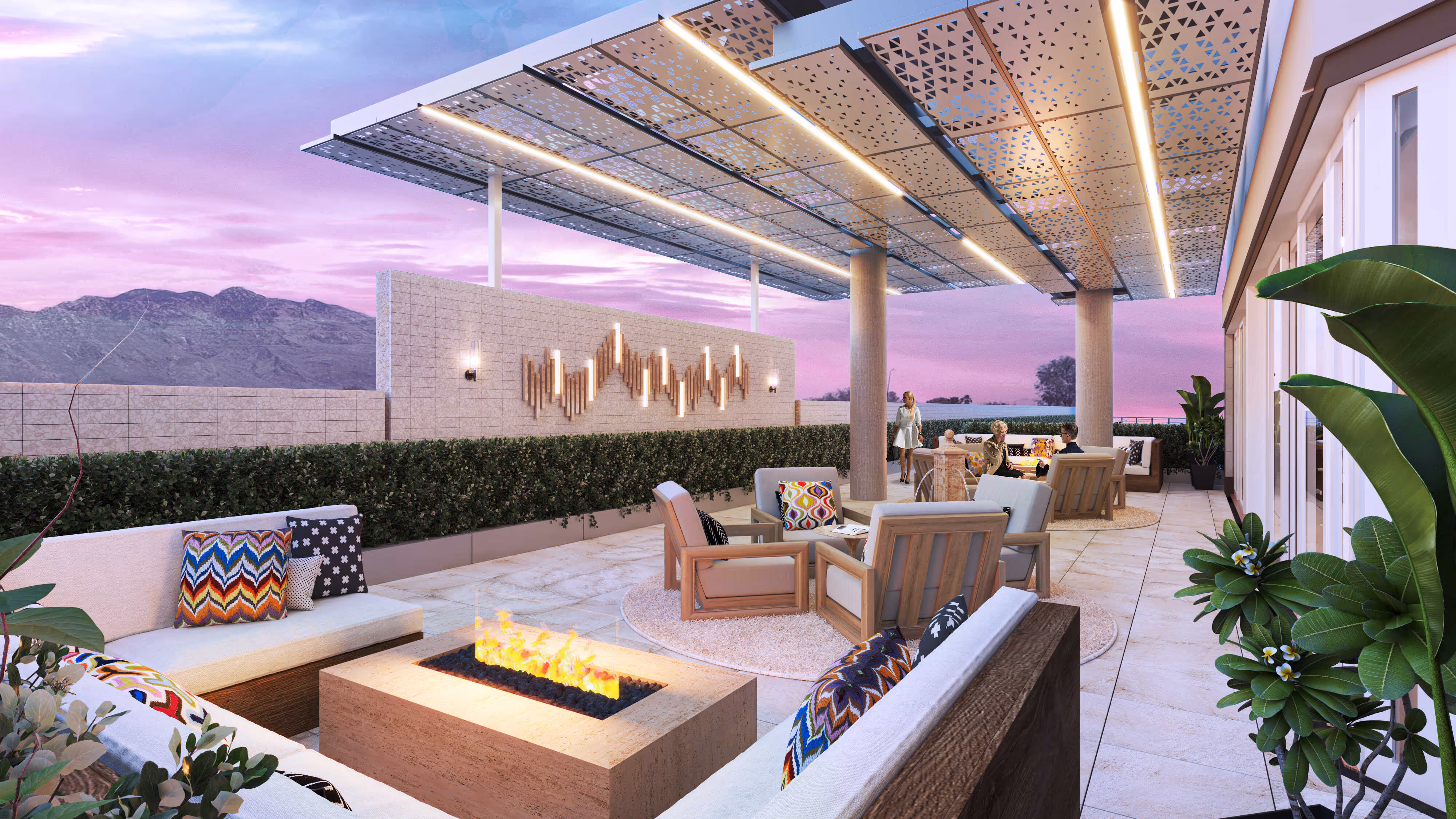 Upscale covered rooftop amenity deck at sunset with a large fire pit, comfortable seating, and custom modern light fixtures at The Astrie in Tucson, AZ.