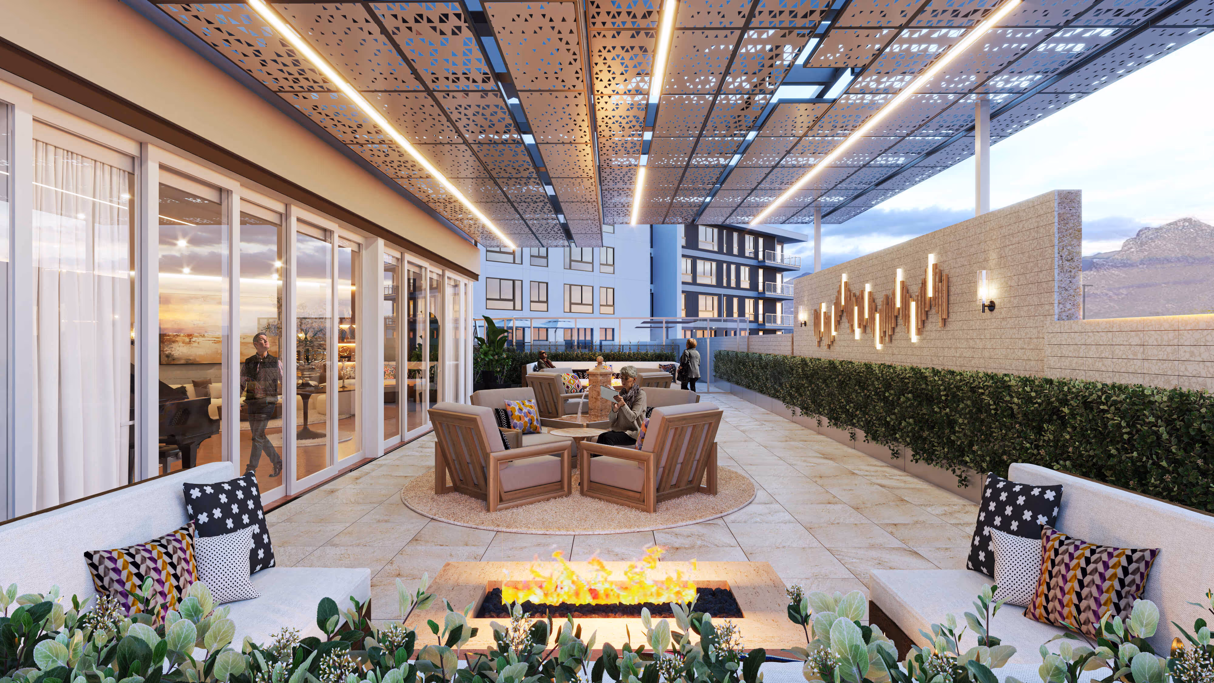 Covered rooftop lounge and patio with a large built-in fire pit, modern outdoor seating, and mountain views at The Astrie in Tucson, AZ.