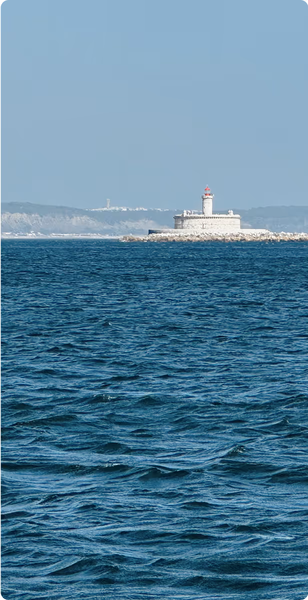 View of Santa Marta Lighthouse in Cascais, Portugal, seen from the sea with blue ocean waves.
