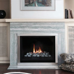 Montigo Direct Vent Flush Face Single Sided Fireplace H38 with clean-face design, featuring decorative charcoal river rocks and flames visible, set in a modern living space with a stylish surround.