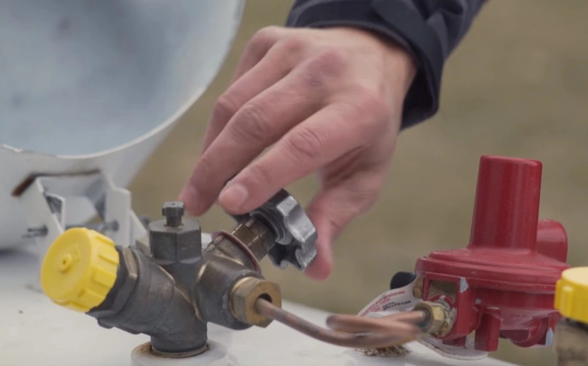Hand turning off propane tank valve.