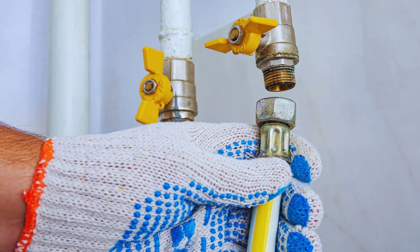 Hand connecting yellow gas line pipe.