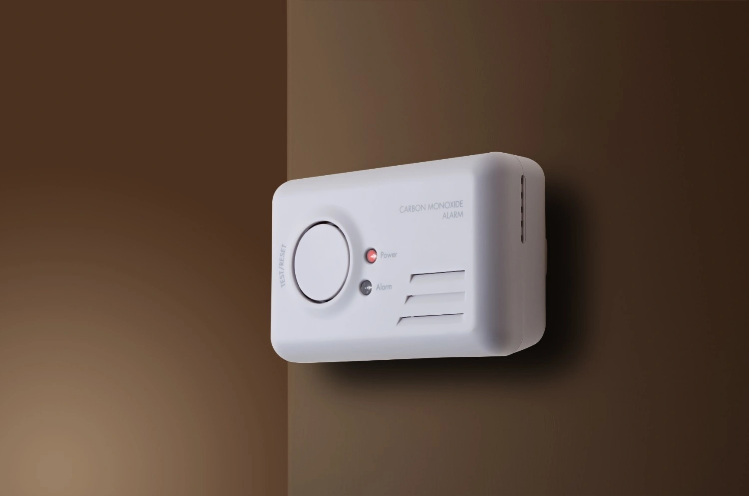 Wall-mounted carbon monoxide alarm with test/reset button, power and alarm indicators, and intake vents.