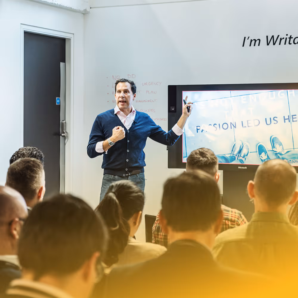 A woman pointing to colorful sticky notes on a whiteboard while three colleagues watch during a brainstorming session.