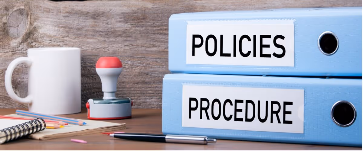 Two labeled folders titled "POLICIES" and "PROCEDURE" along with some office items – symbolizing administrative documentation and governance.
