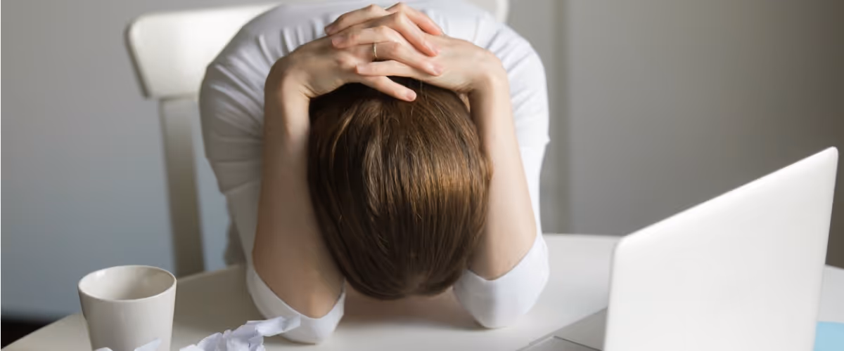 portrait-of-a-woman-grabbing-her-head-near-the-laptop-picture-id615739334