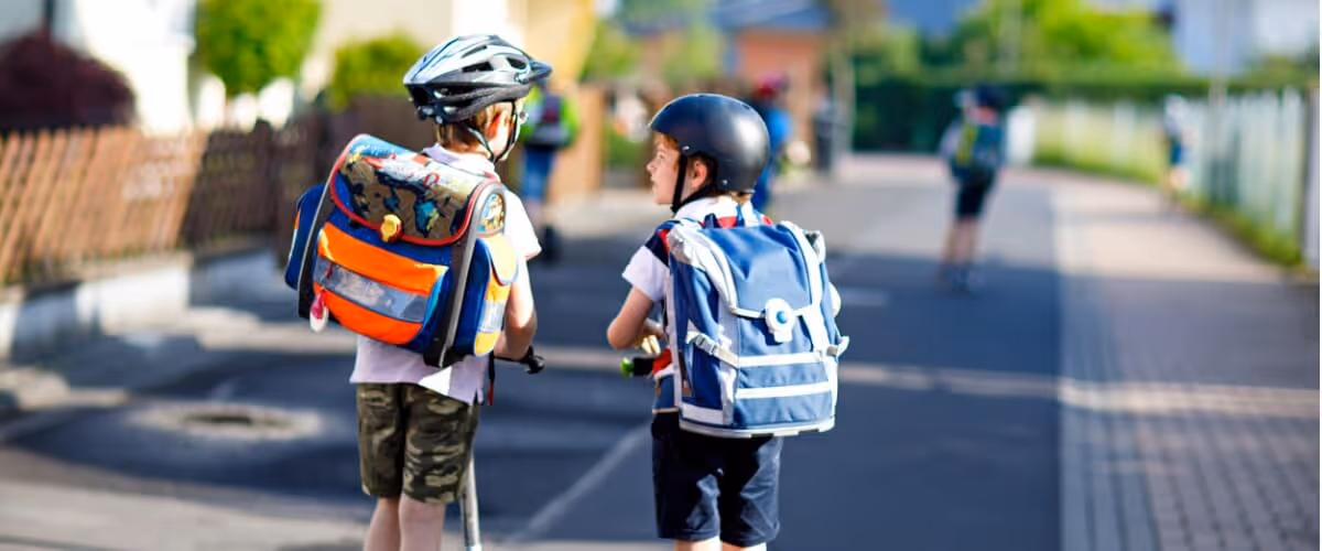 two-school-kid-boys-in-safety-helmet-riding-with-scooter-in-the-city-picture-id973261704