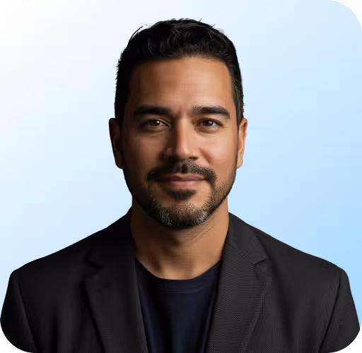 Portrait of a man with short dark hair and beard wearing a black blazer and shirt.