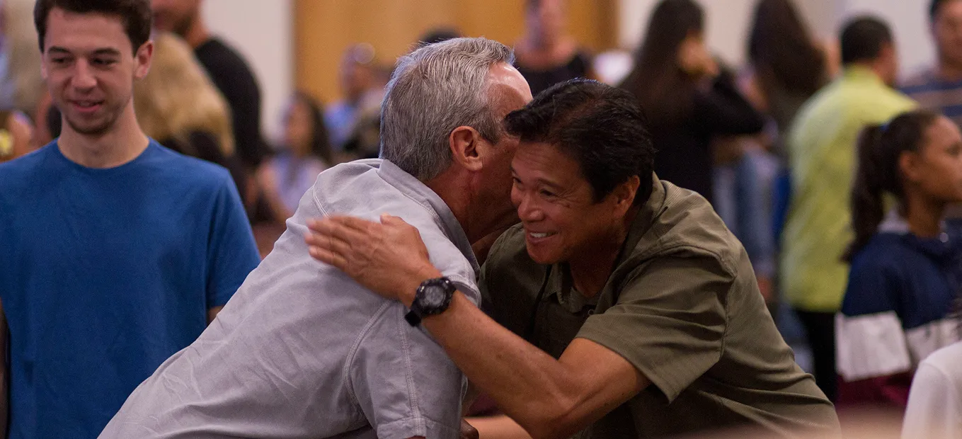 Men hugging amongst a group of people