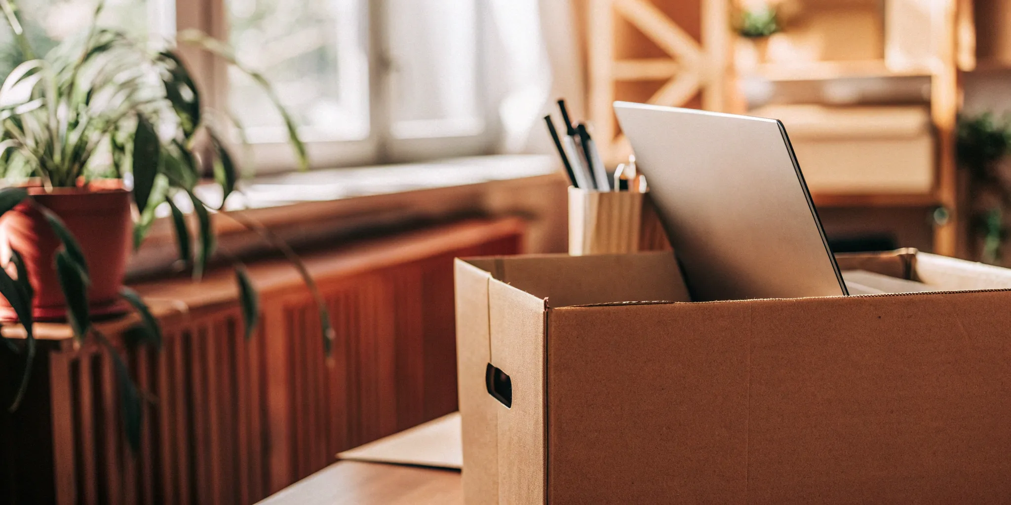 Office relocation checklist: Laptop, supplies, and box on desk.
