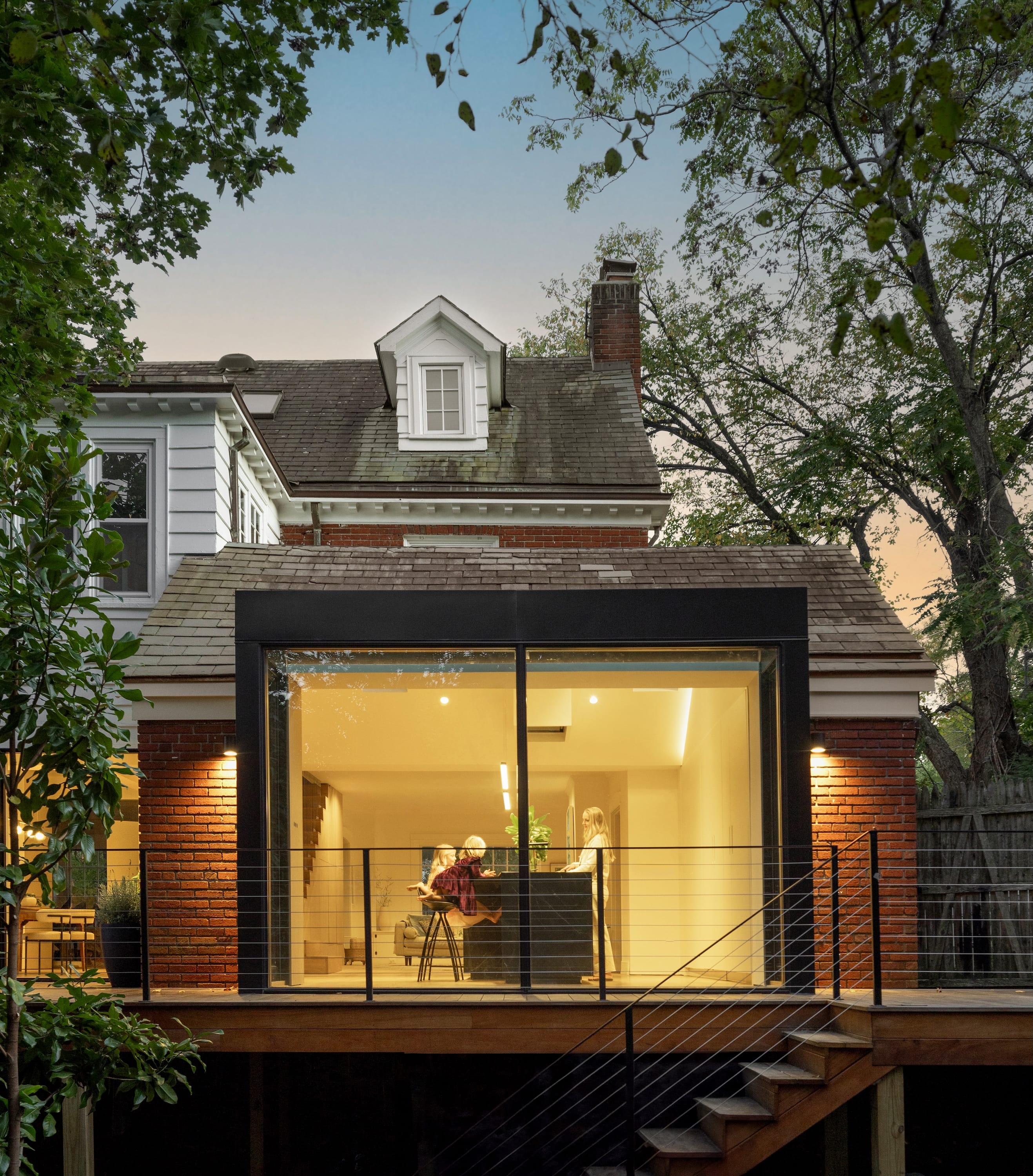 Modern home extension with glass walls and warm interior lighting.