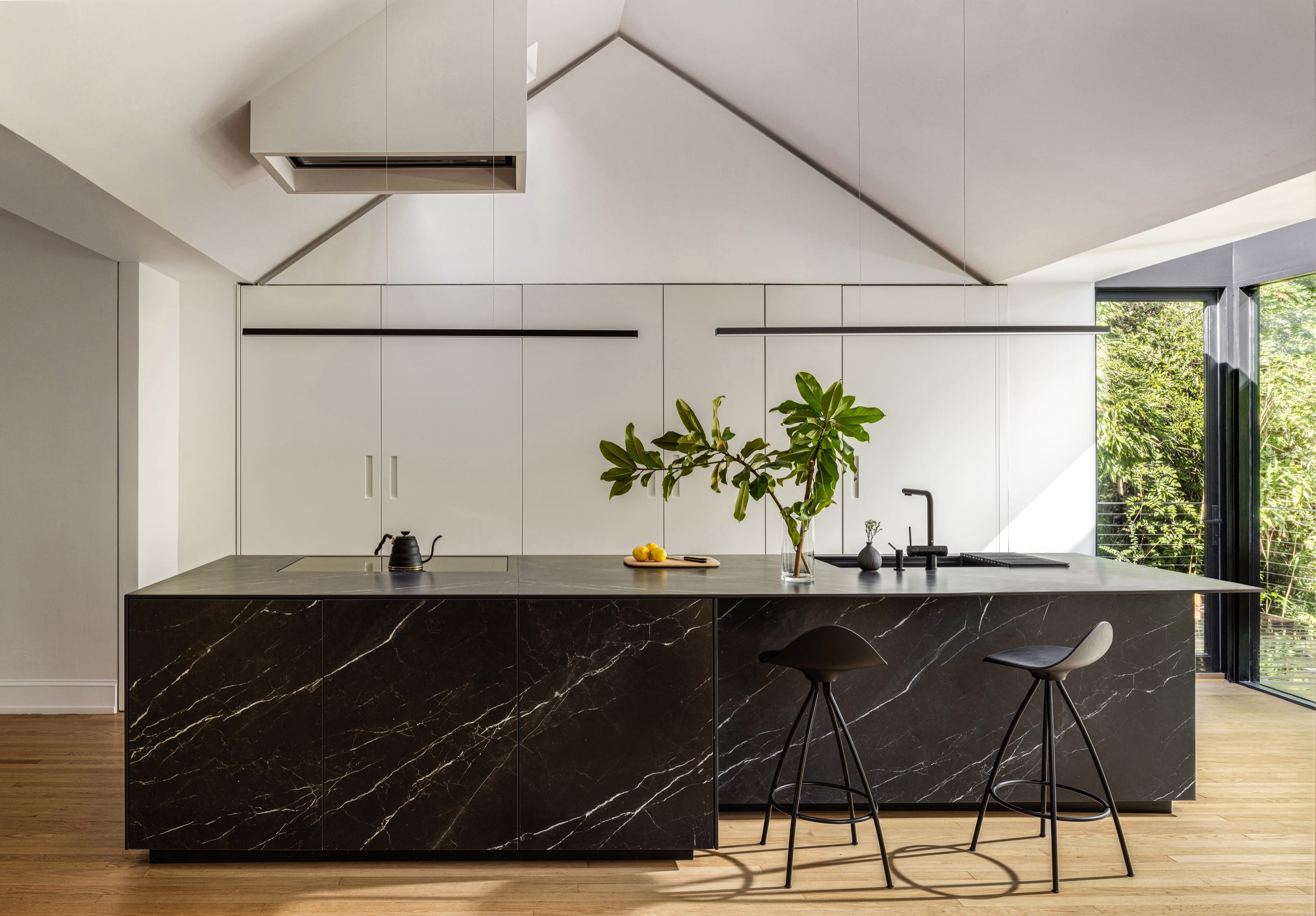 Modern kitchen with black marble island and wood flooring.